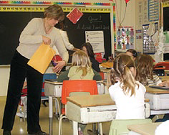 Situation de classe. Deux adultes qui circulent pour distribuer des objets aux élèves.