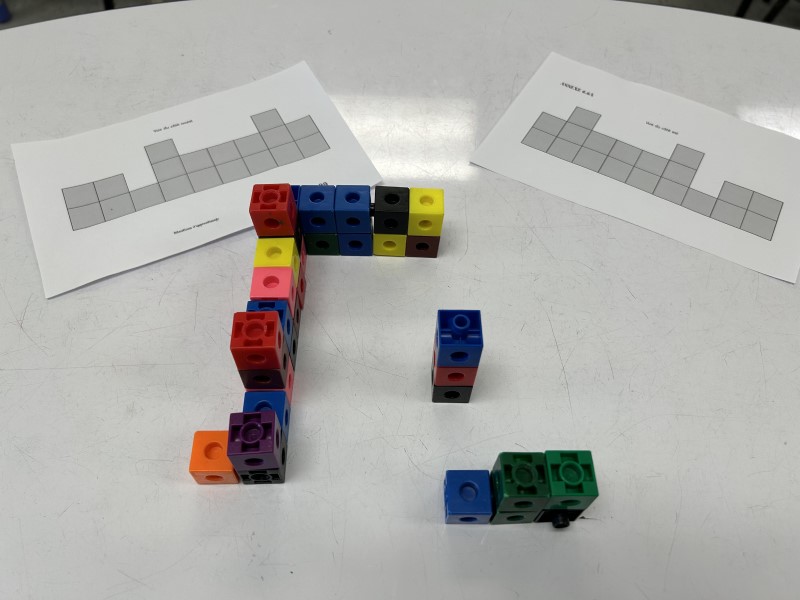 Models of square structures on sheets of paper are reproduced with interlocking blocks